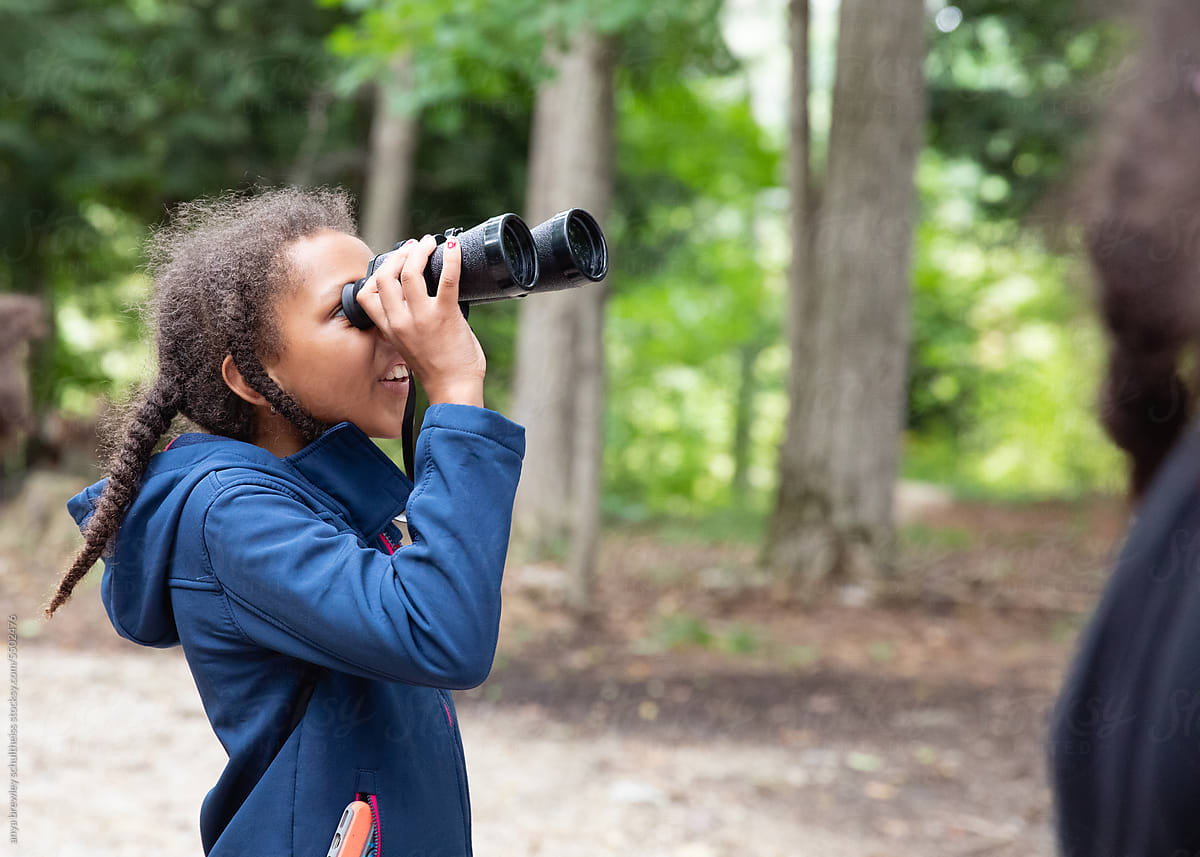 Child looking through a pair of binoculars while at camp