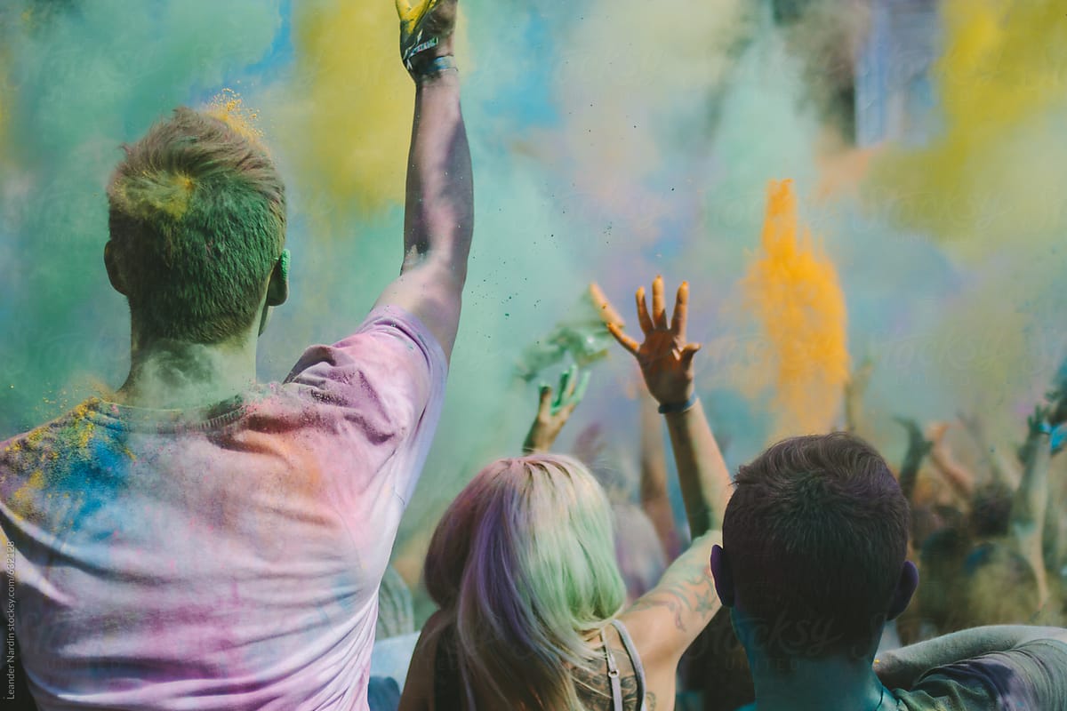 crowd throwing colorful powder and dancing at an outdoor music festival