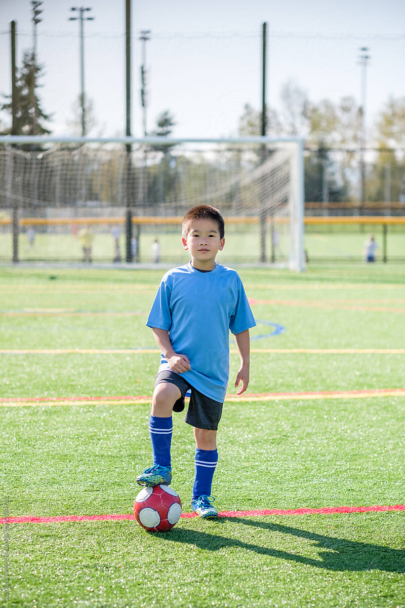 Asian Boy Standing Over a Soccer Ball