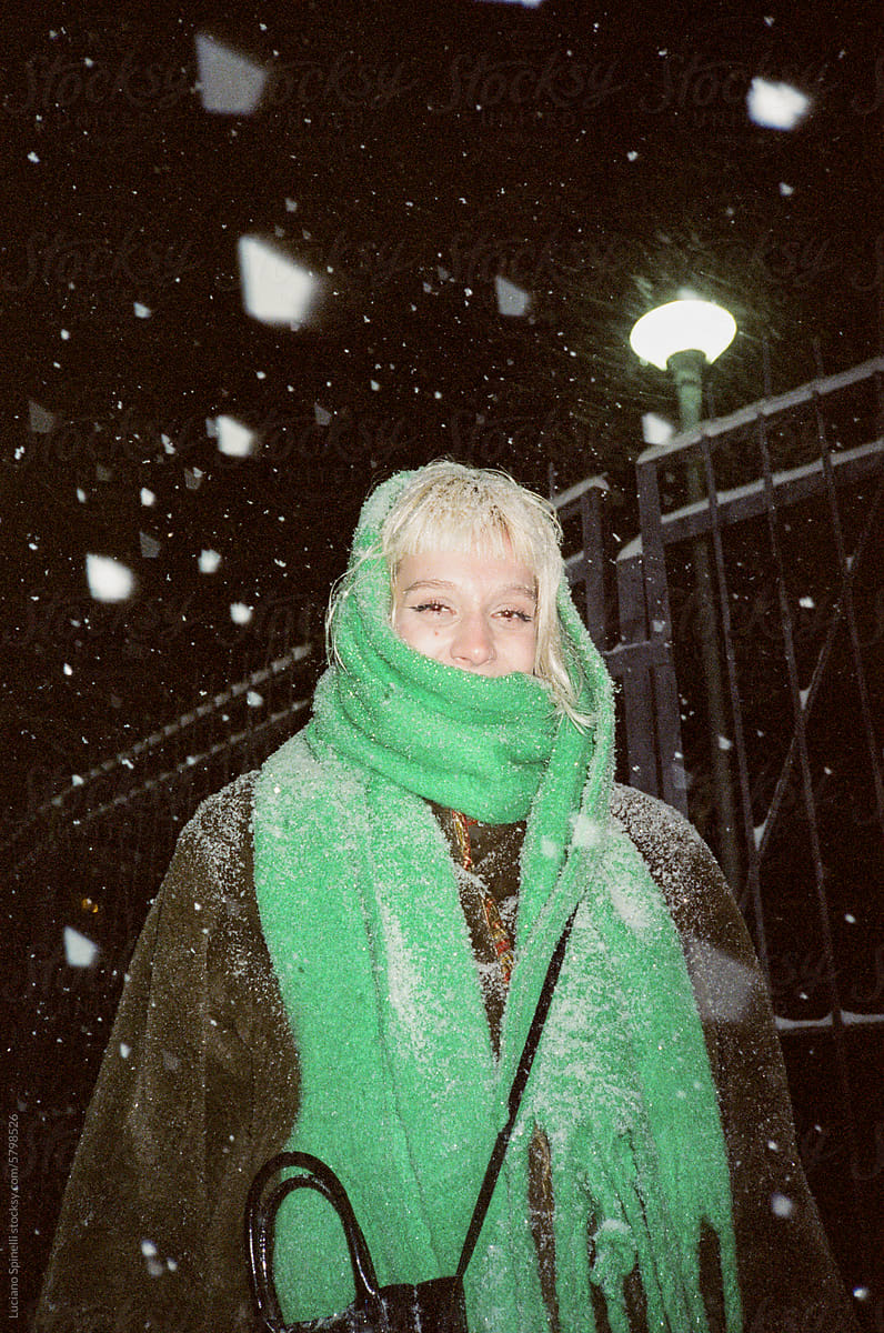 Portrait of happy model in the snowstorm with eye contact look camera