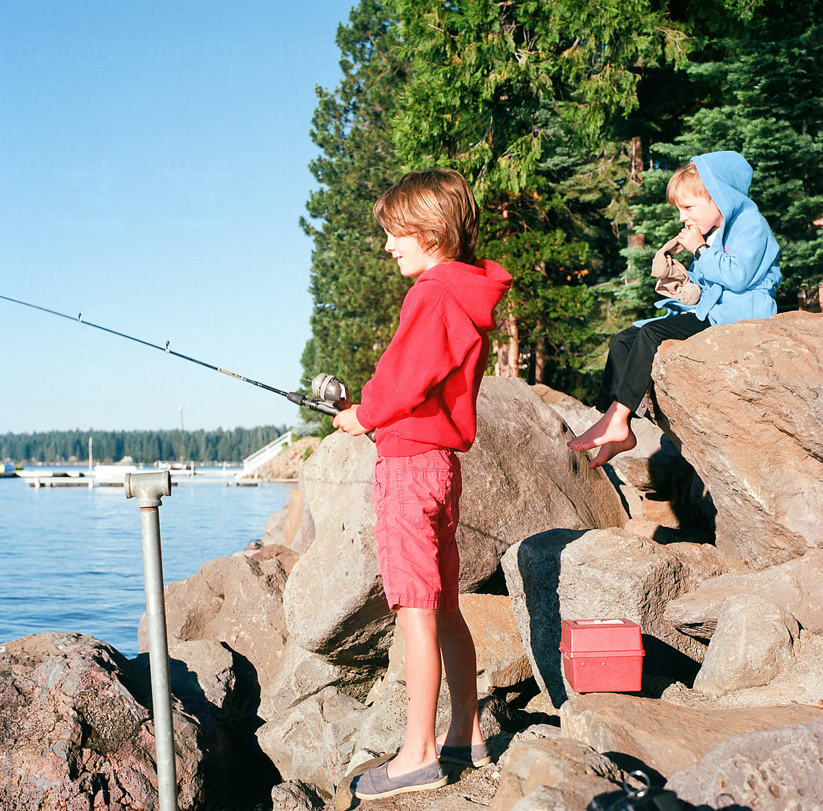 Young boy fishing on Lake Almanor while little brother watches
