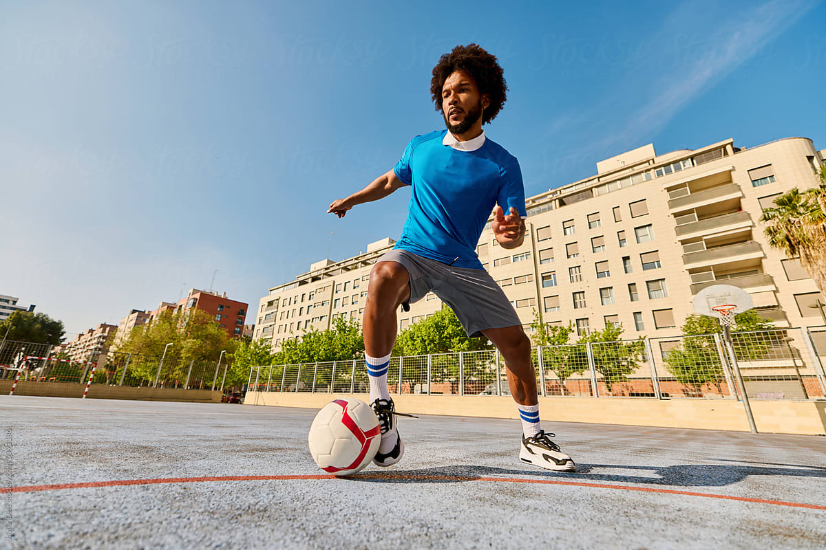 Energetic black football player kicking ball