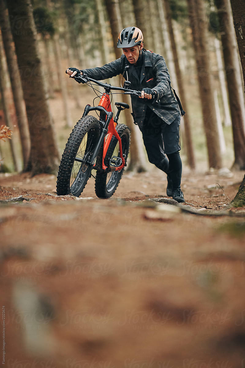 Mountain biker pushing his bike along a forest path
