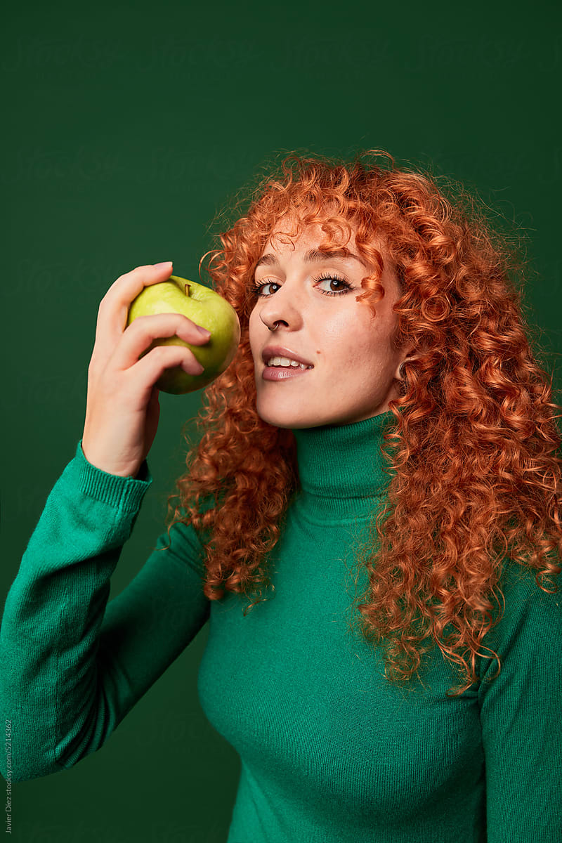 Cheerful ginger woman eating apple