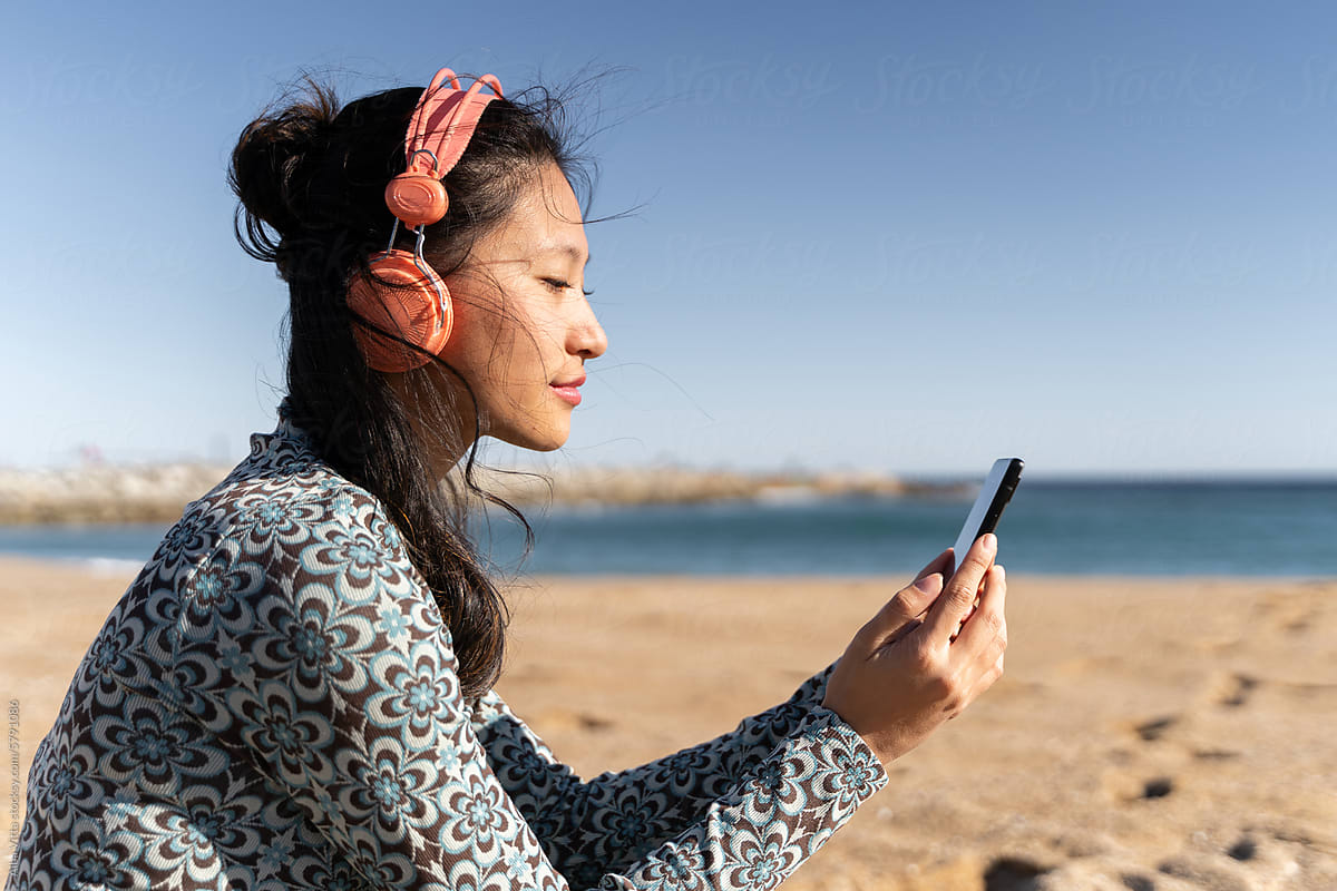 Woman with headphones and phone at beach