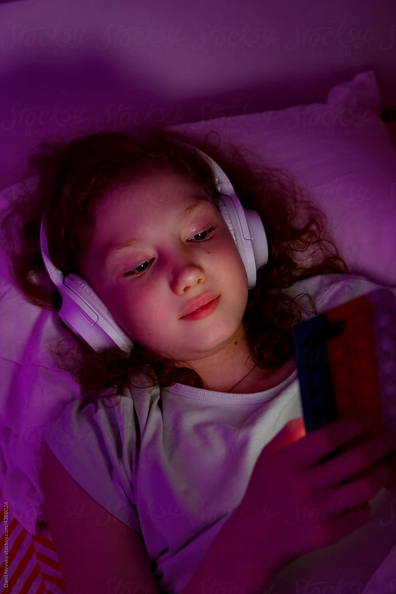 Girl listening to music on bed at night