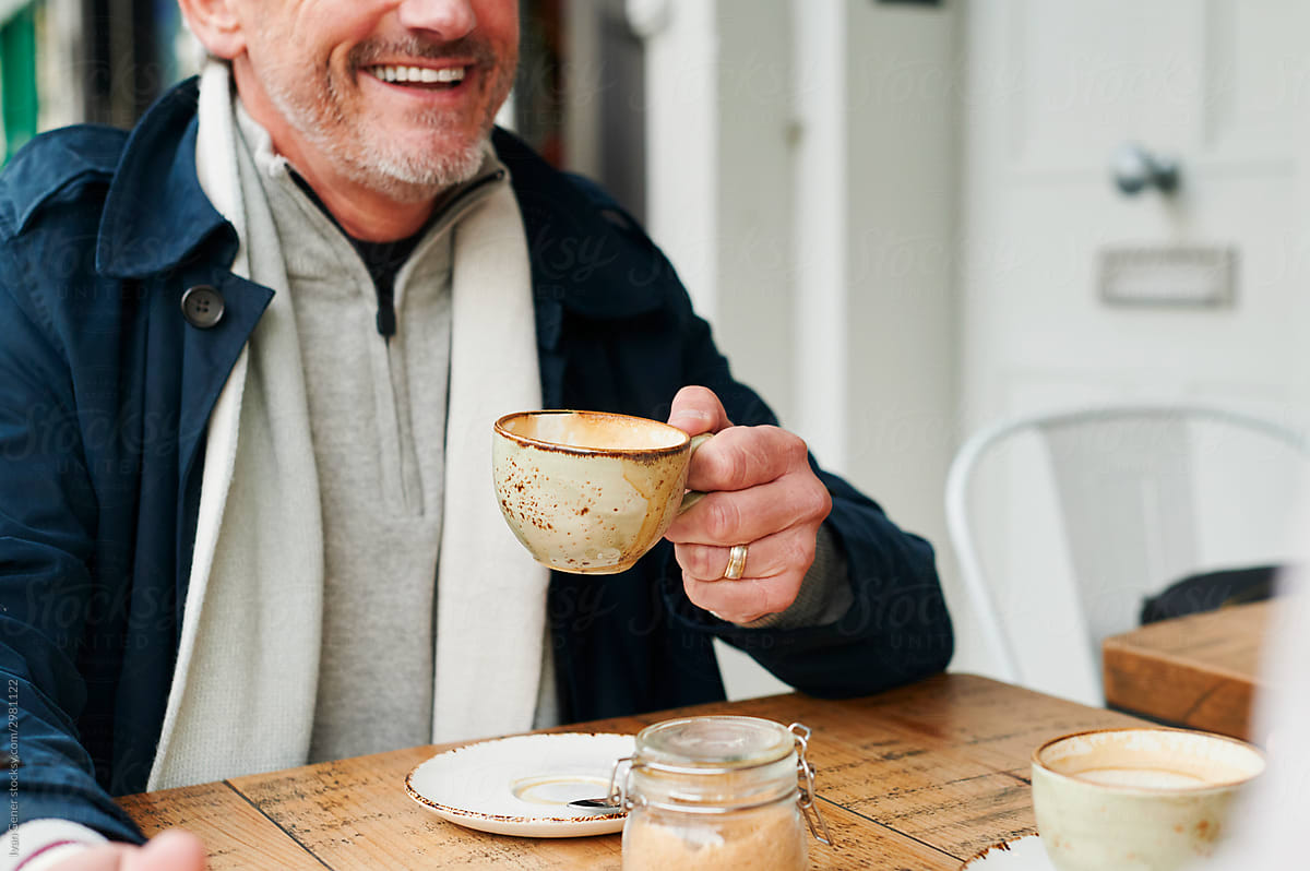 Laughing mature man drinking coffee outside