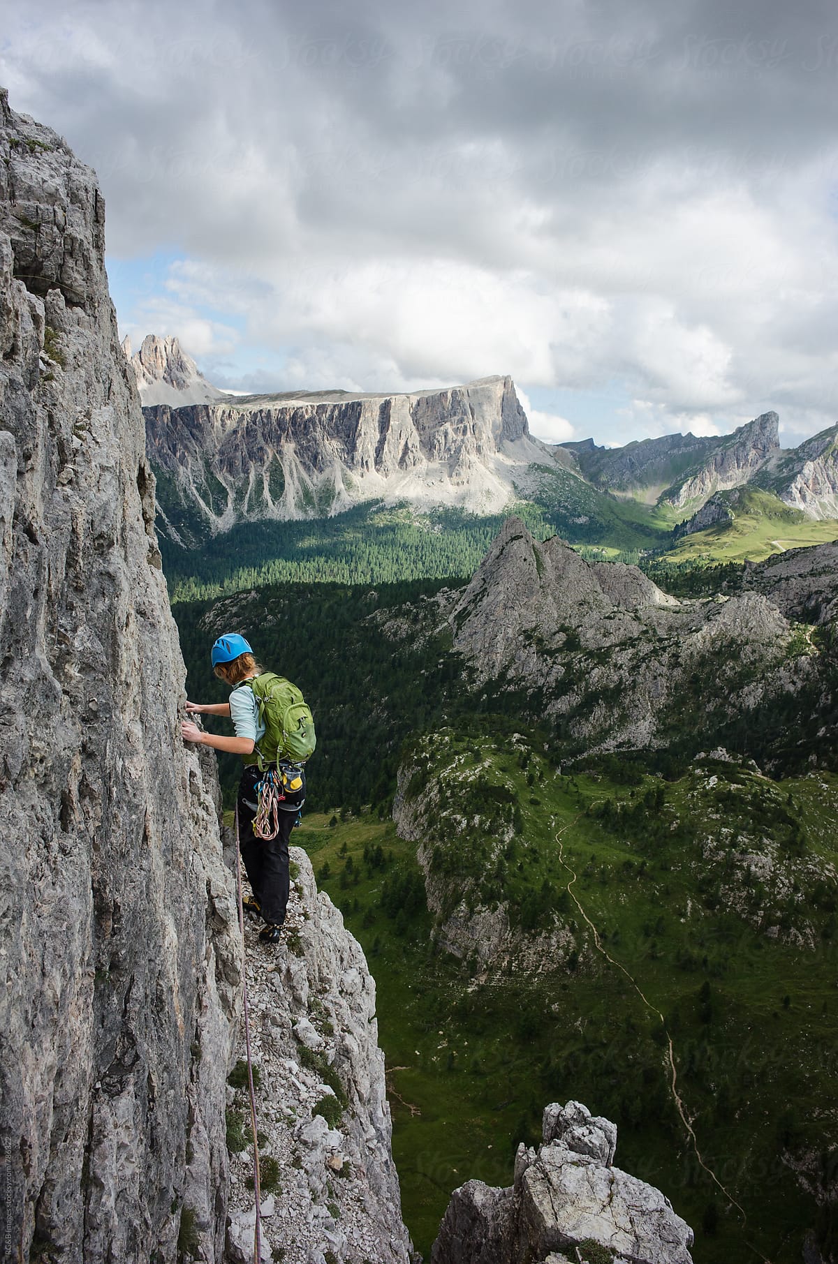 Female alpinist walking along a narrow ledge, rock climbing outdoor