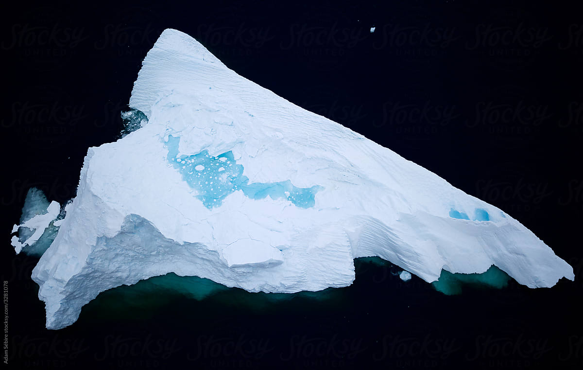 Greenland melts, meltwater pool forms on massive Arctic iceberg, aerial drone birds eye view