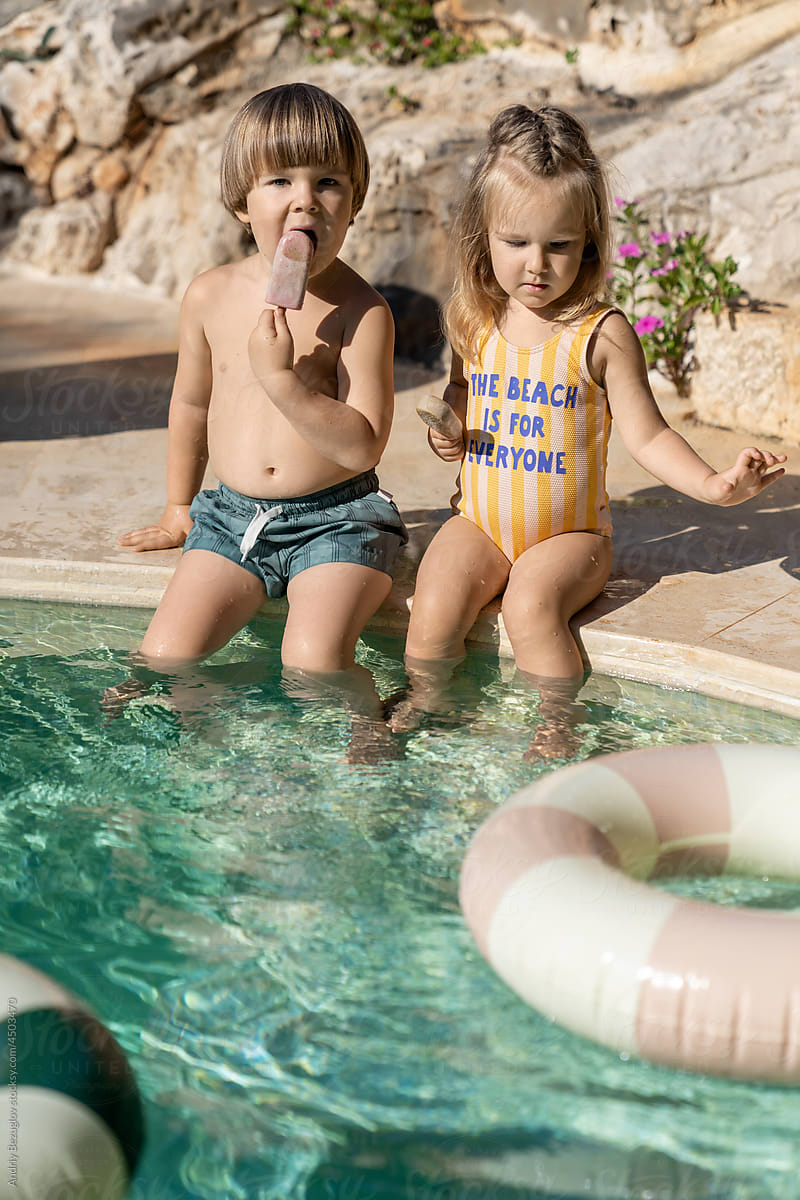 Children in swimsuits eating ice cream in pool outdoors