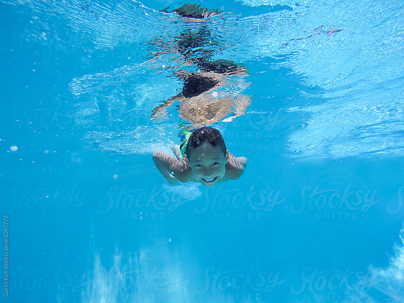 Asian boy swimming underwater smiling