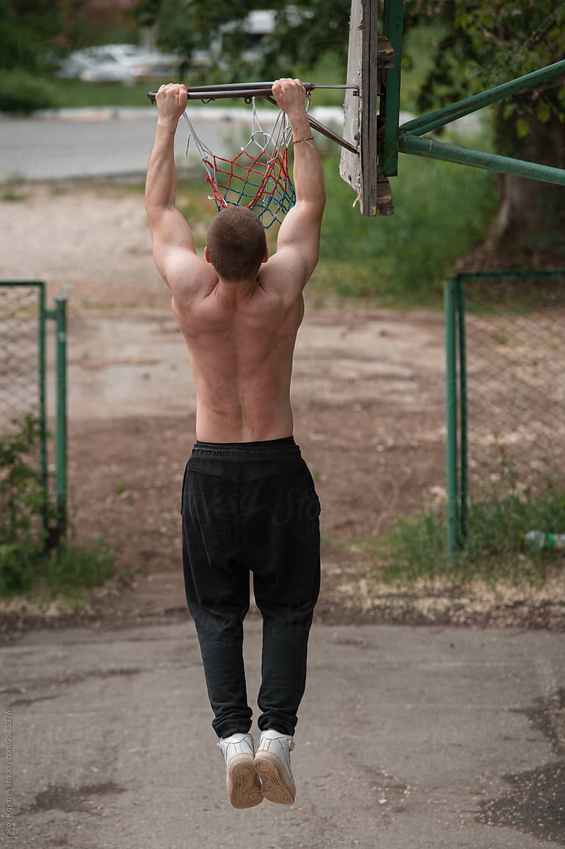 powerful street work-out of the crossfit athlete - doing pull-ups on a basketball ring