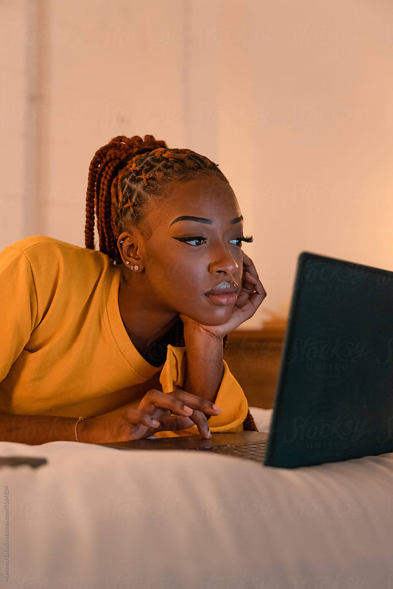 Black woman using laptop on bed