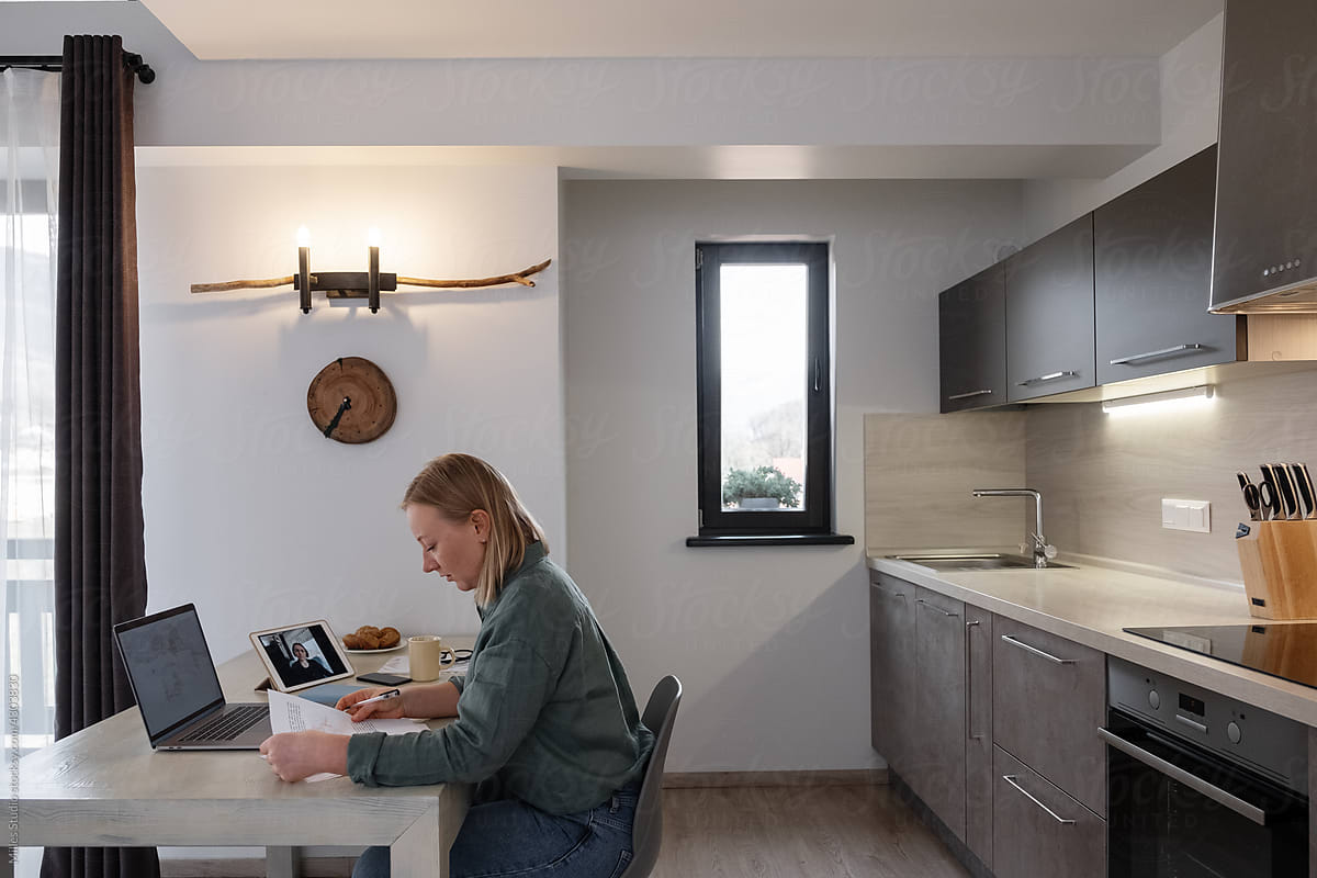 Businesswoman reading papers in kitchen