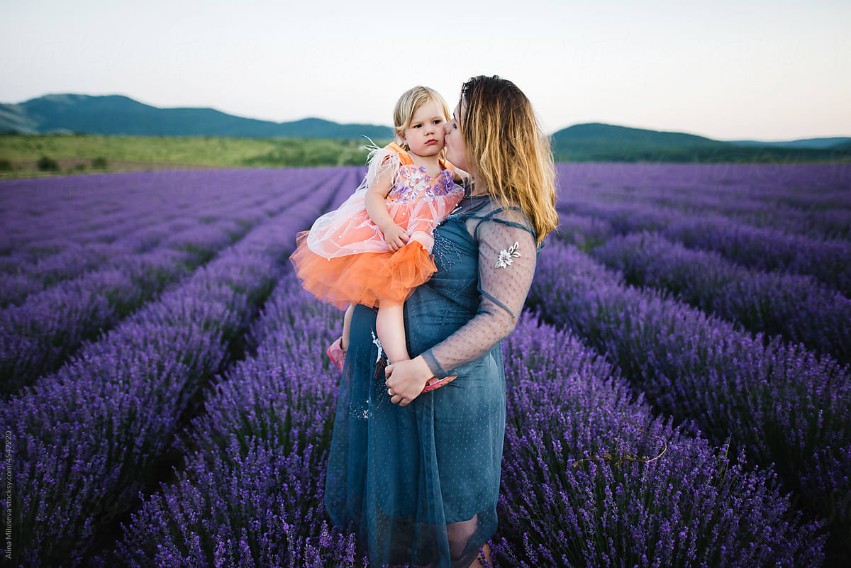 Mom kissing daughter in blooming lavender field