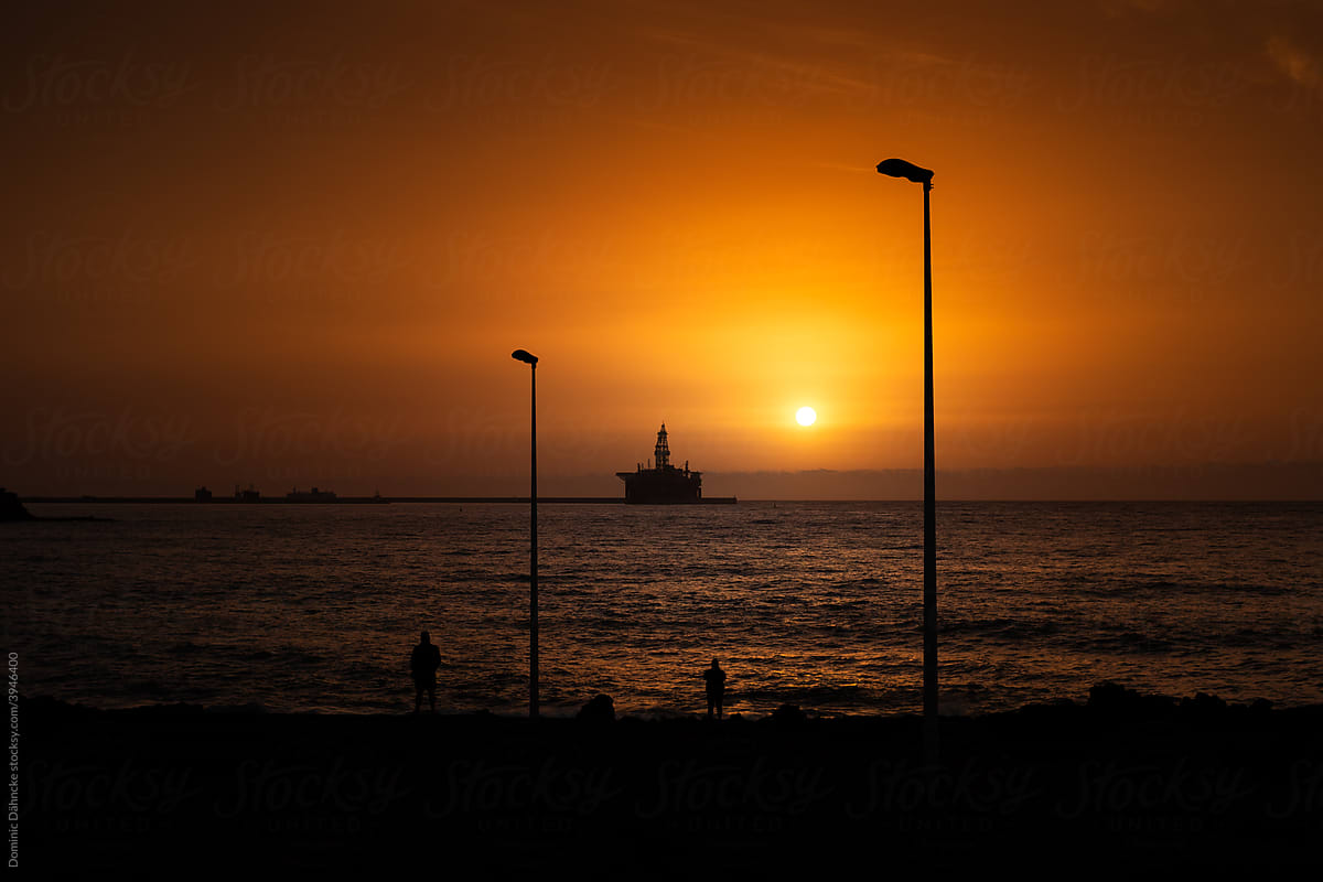 An oil rig at dawn next to a lamppost.