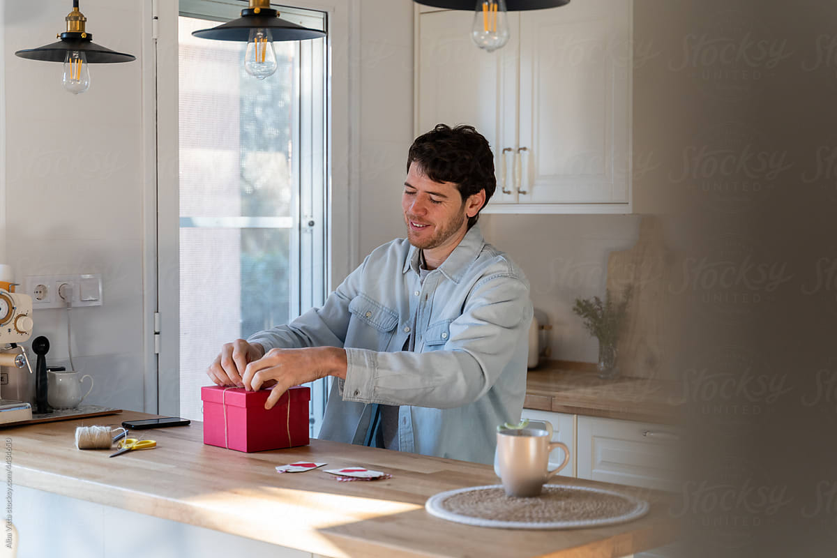 Man packing gift in modern kitchen