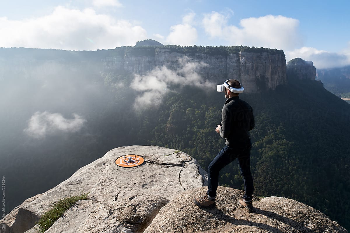Man in vr glasses controlling drone from mountain