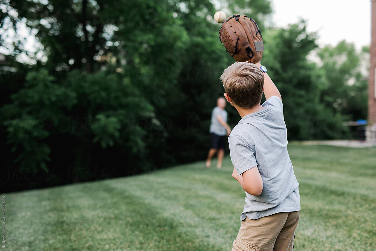 10. Little boy with blonde hair and baseball cap playing catch with his dad - wide 1