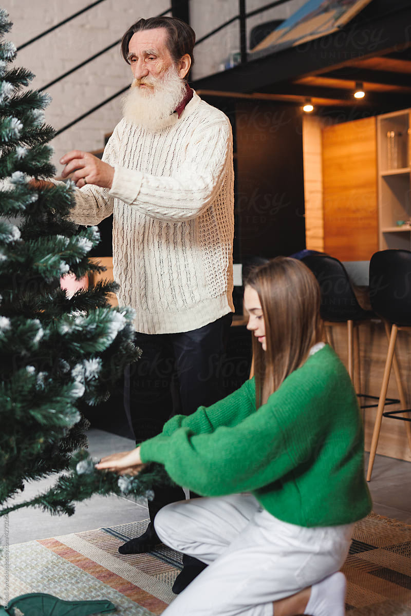 Family aligning artificial fir tree before decorate it