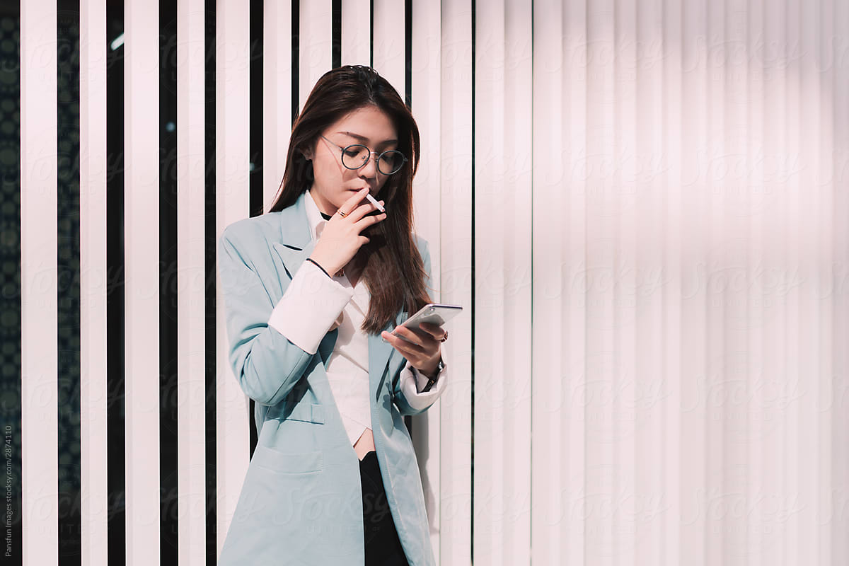 Stylish business woman smoking with mobile phone