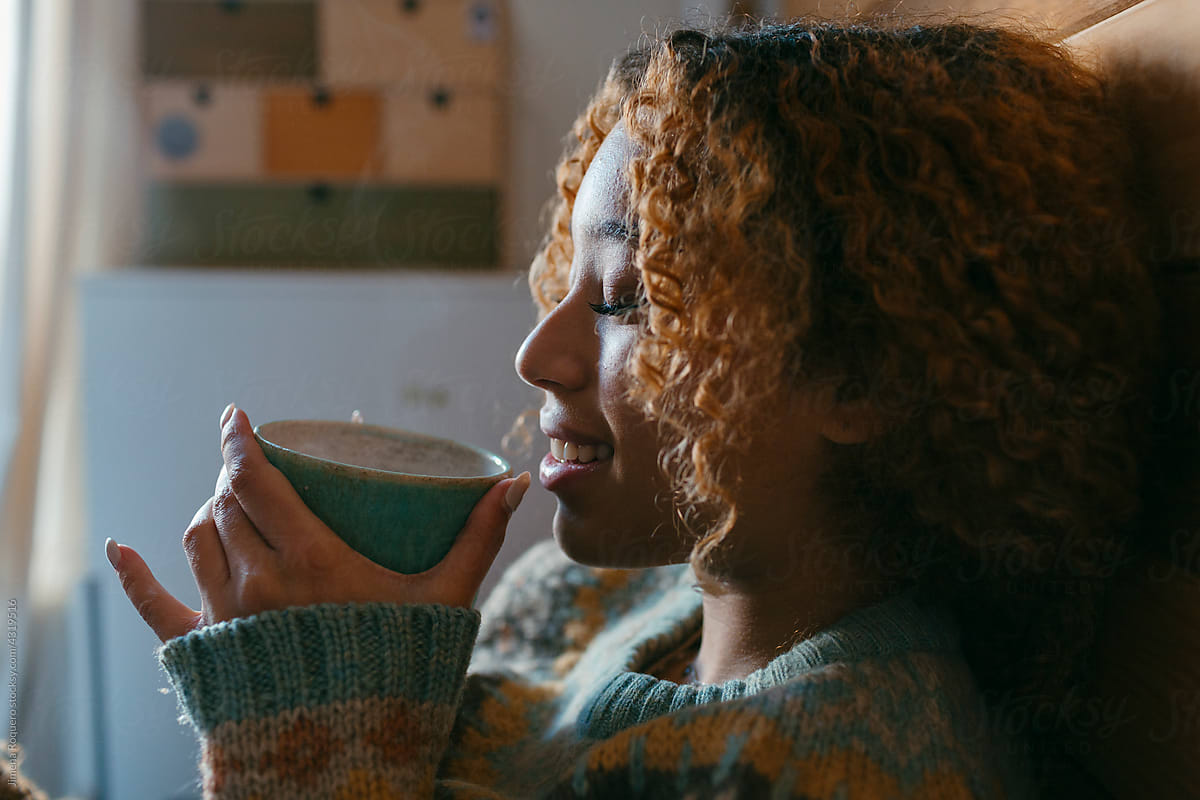 woman drinking hot beverage in the bedroom smiling
