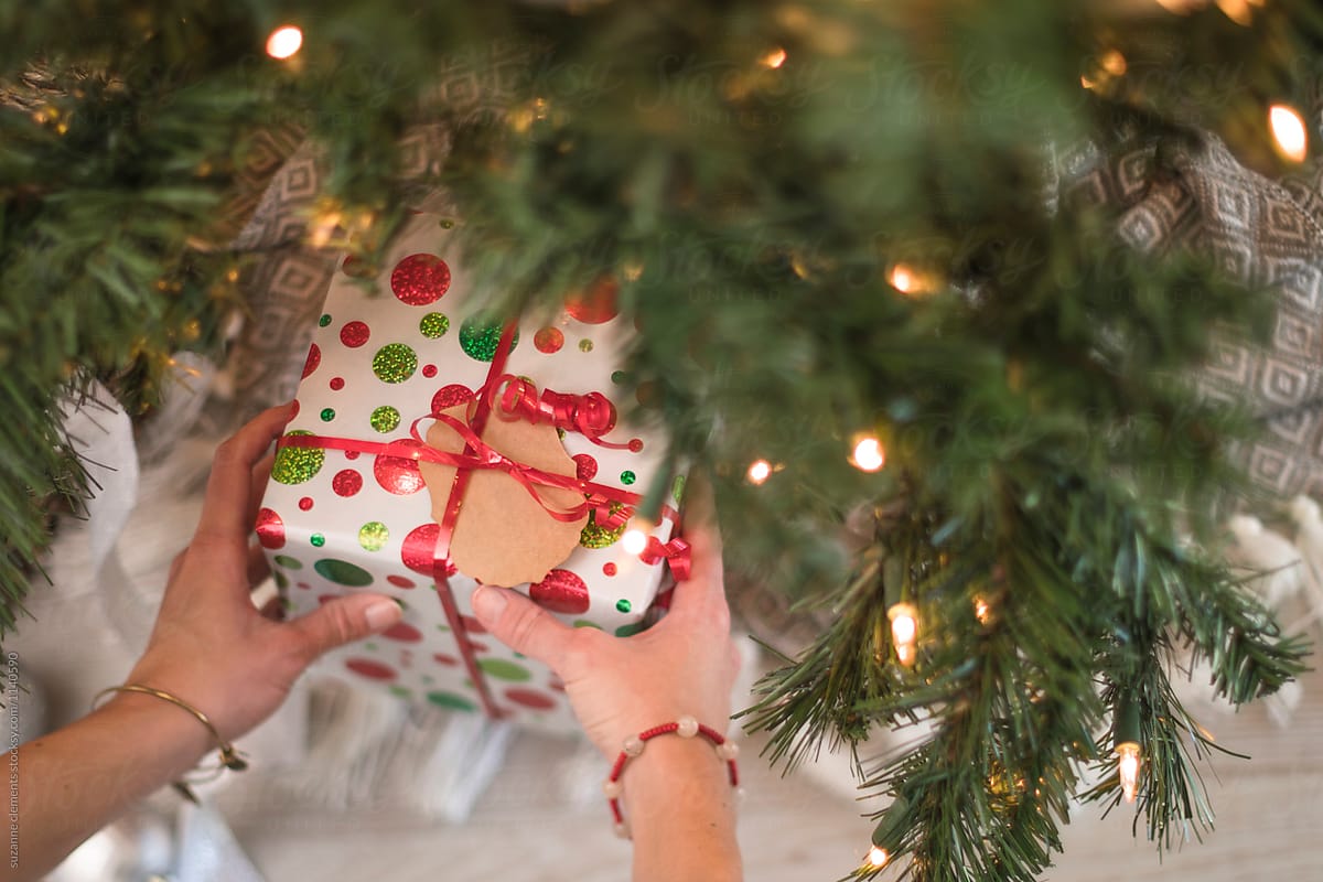 Woman Places Gift Under the Christmas Tree