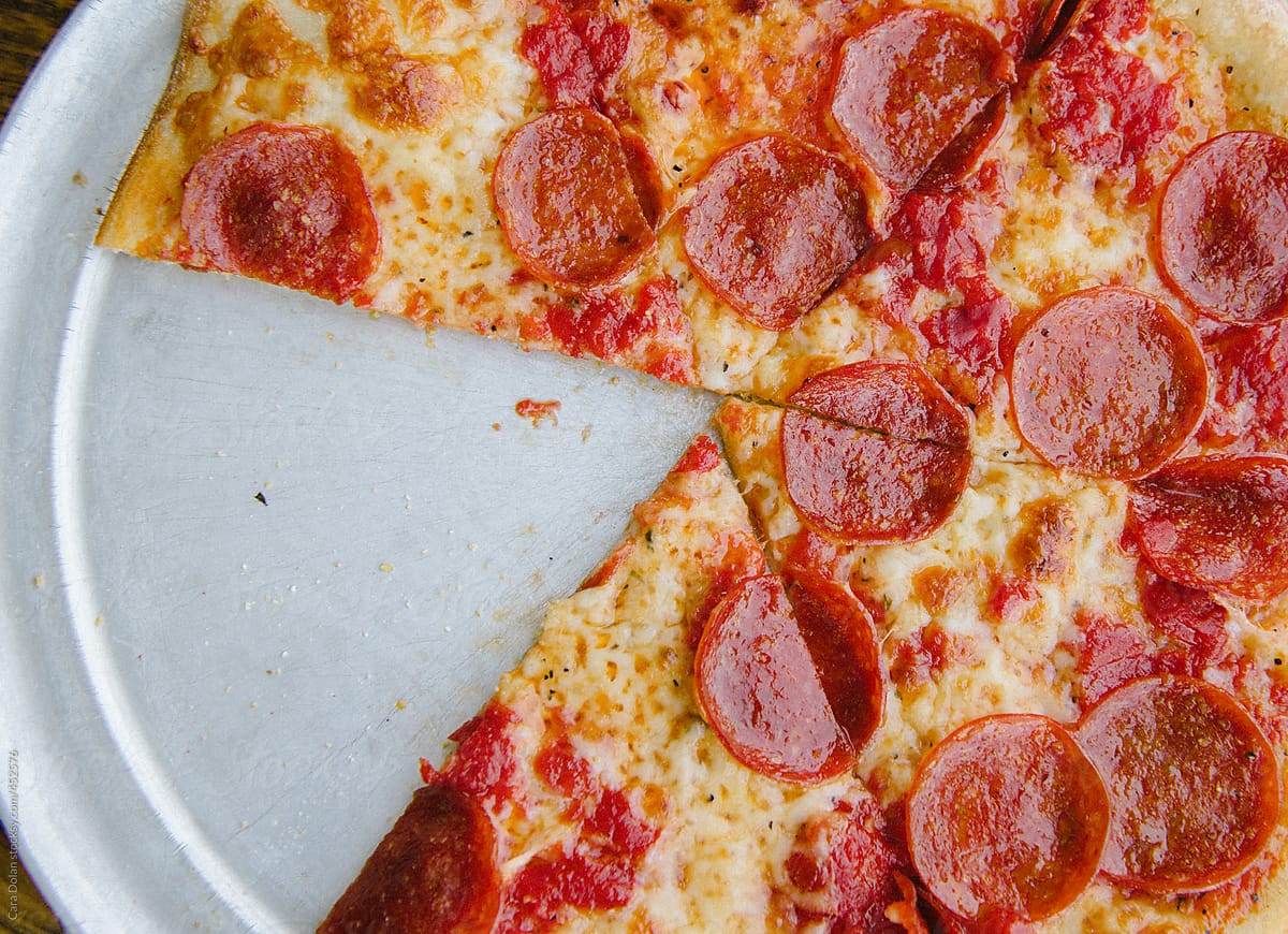 "Pepperoni Pizza With One Slice Taken Out" by Stocksy Contributor "Cara Dolan" - Stocksy