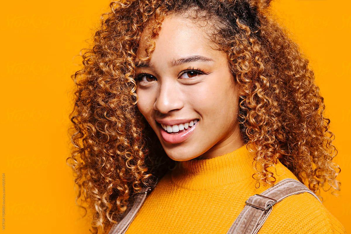 Cheerful woman with curly hair smiling and looking at camera