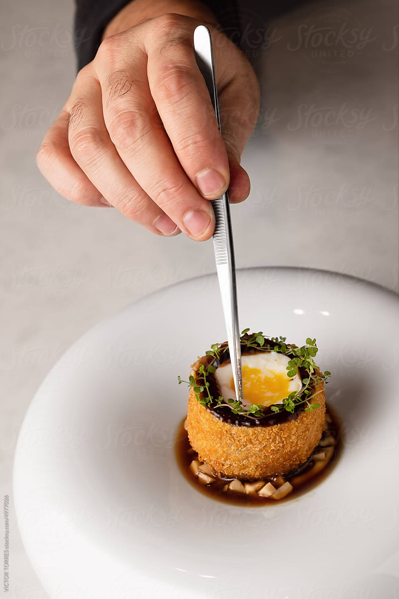Crop chef decorating a scotch egg recipe with herbs