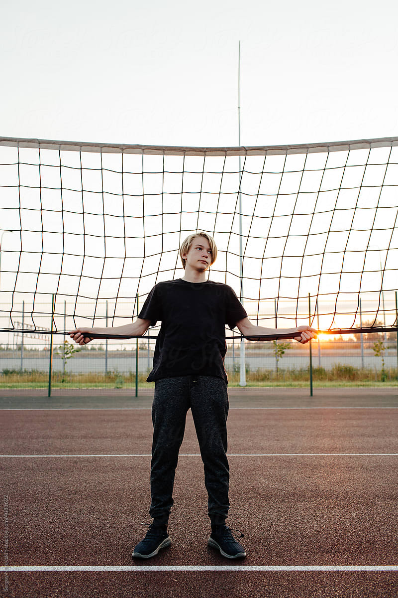 Teenager standing near net on sports ground