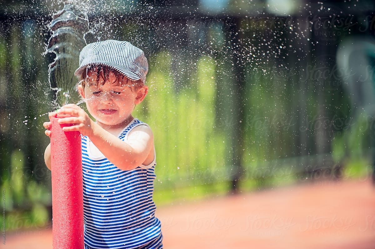 Small boy has fun playing with a water toy outside on a hot day