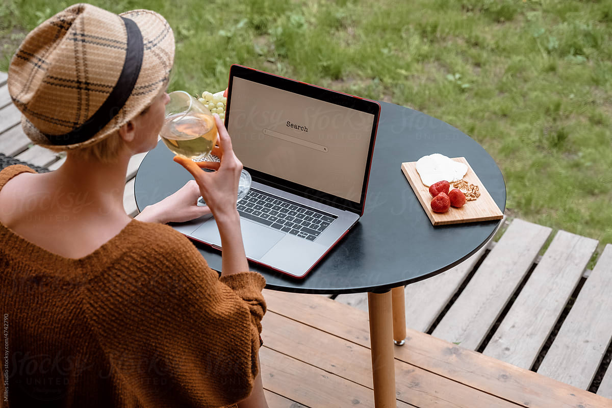 Woman drinking wine and using laptop in weekend