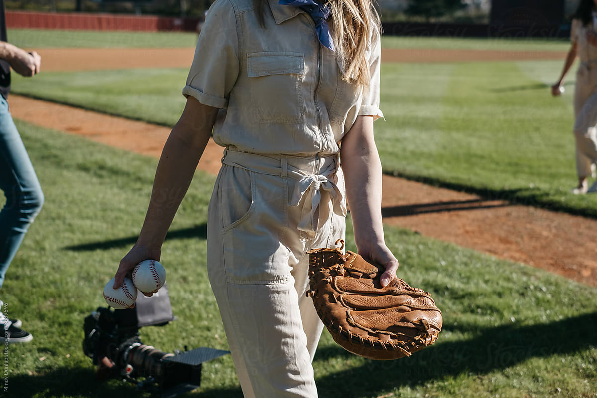 Young woman holding baseballs and glove