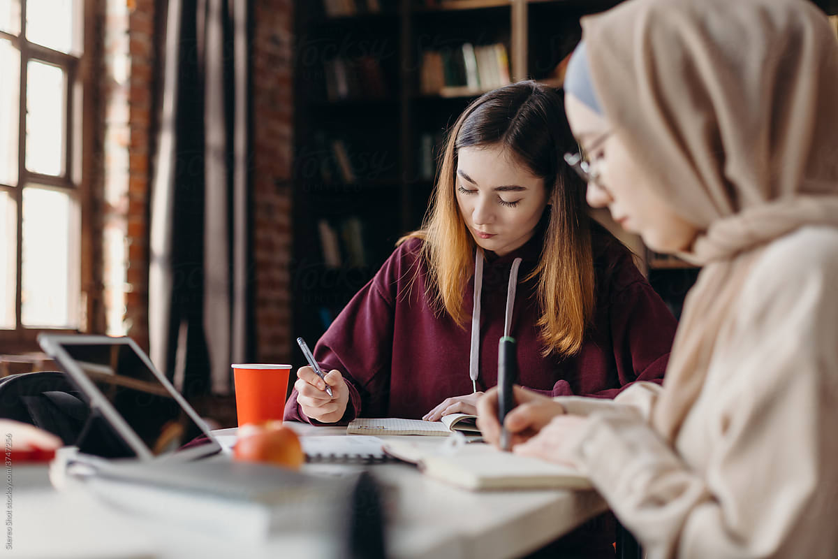 Serious female students fulfilling assignment together in library