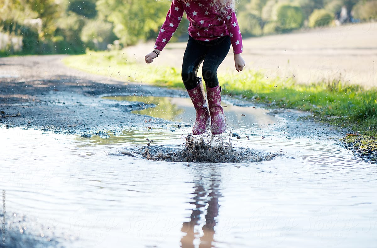 Girl leaping into a puddle