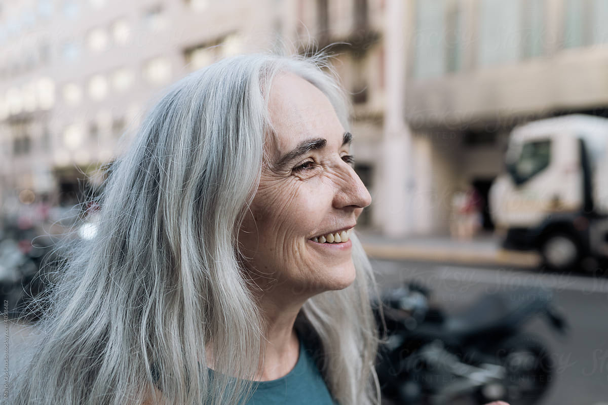 Cheerful grey-haired woman walking in the city