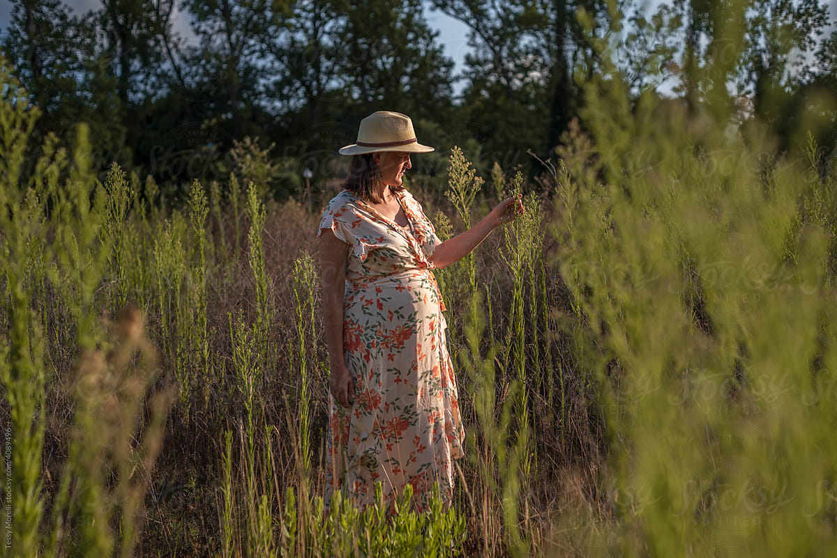 Candid portrait of mum to be walking in the field