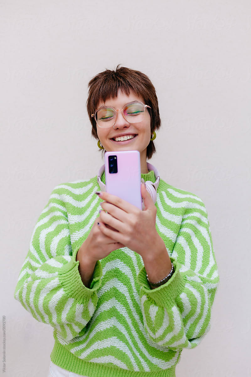 Happy woman taking pictures with smartphone in studio