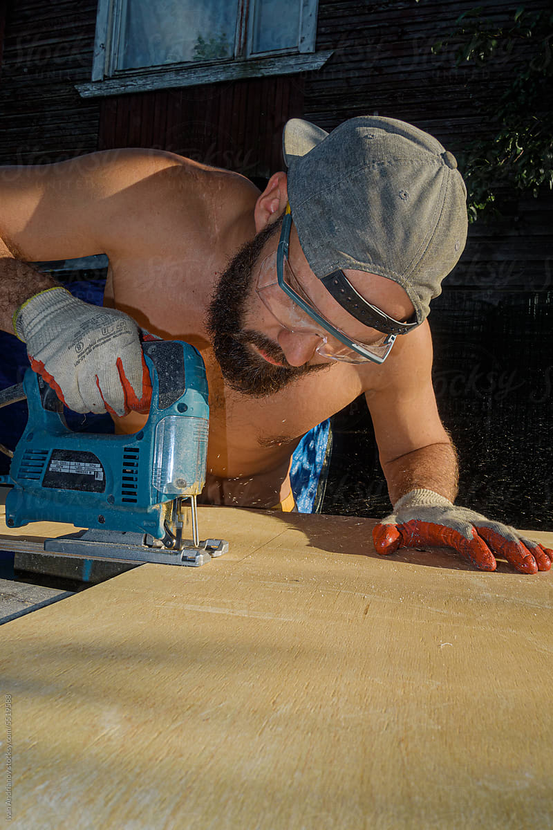 Man Is Working Jigsaw Cutting On Plywood In Summer