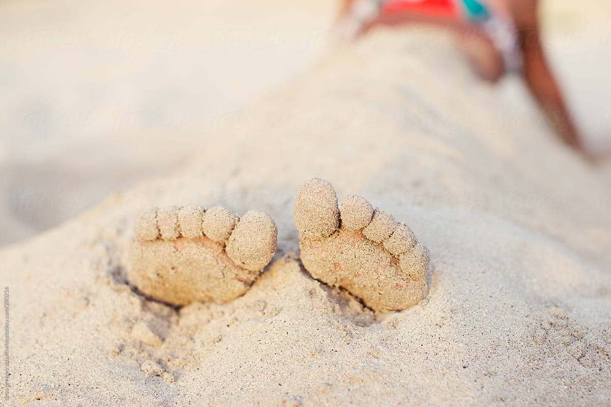 Sandy toes of a young girl sitting on a beach