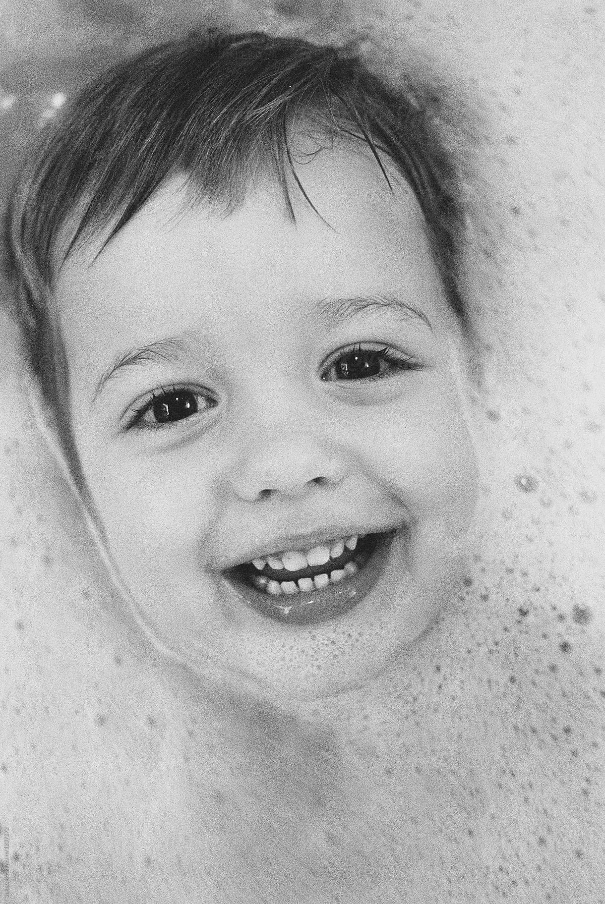 Cute smiling boy in bathtub with his face almost submerged