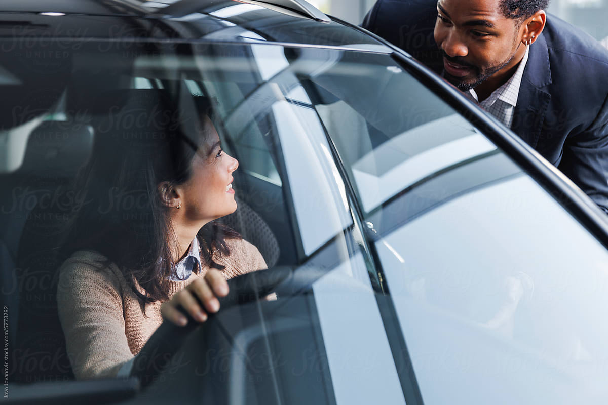 Excited couple discussing while buying new car at dealership
