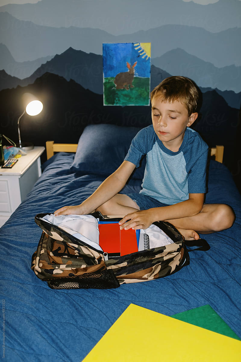 A little boy packing his backpack for school