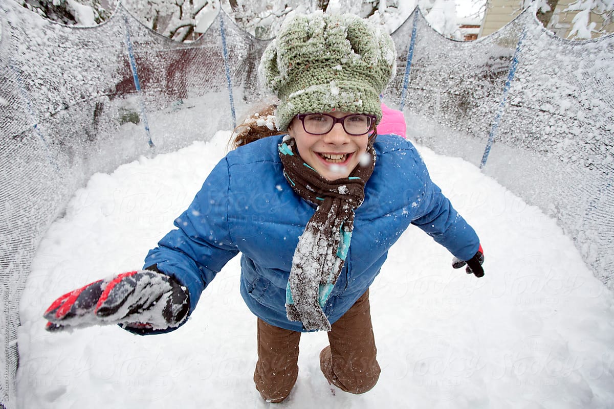 Preteen girl jumps for joy on a snow covered trampoline