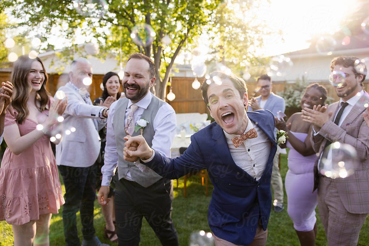 Happy, carefree newlywed gay male couple dancing at wedding rece