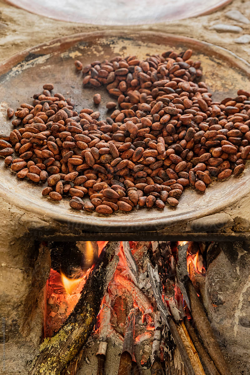 Cacao beans roasting on a comal with the intense fire below