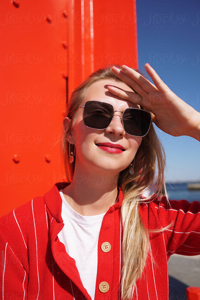 Young blonde girl with red lipstick in sunglasses near the ocean
