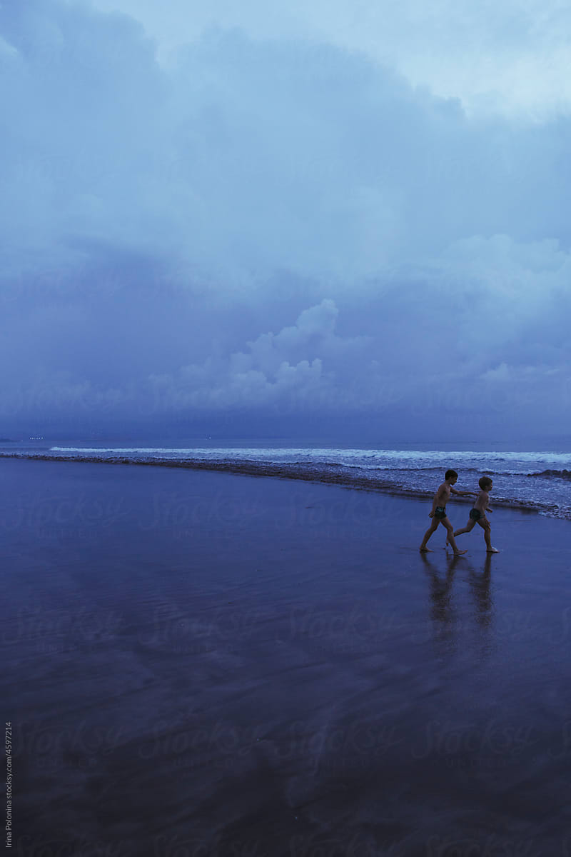 Children walk along seashore.