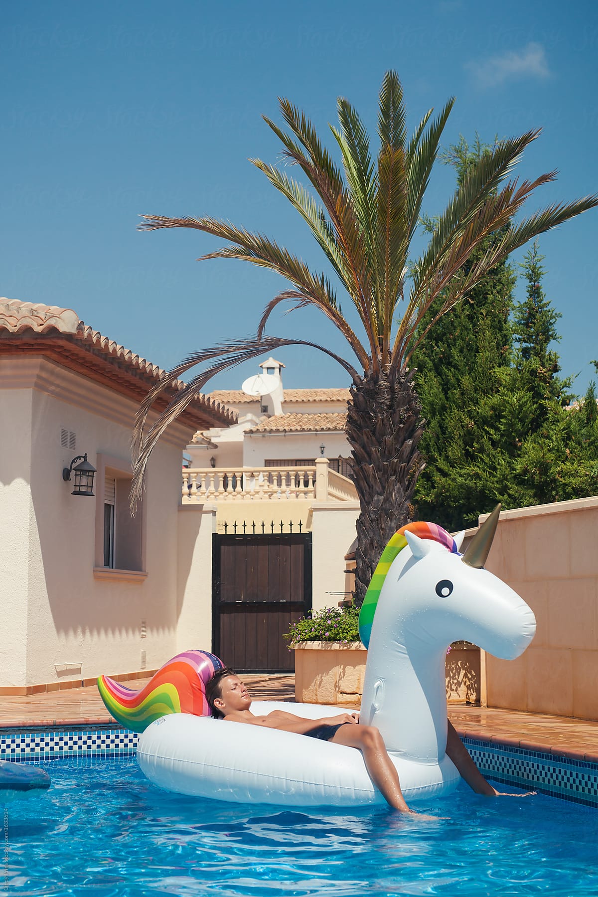 Teen boy lying on a big inflatable unicorn in a swimming pool